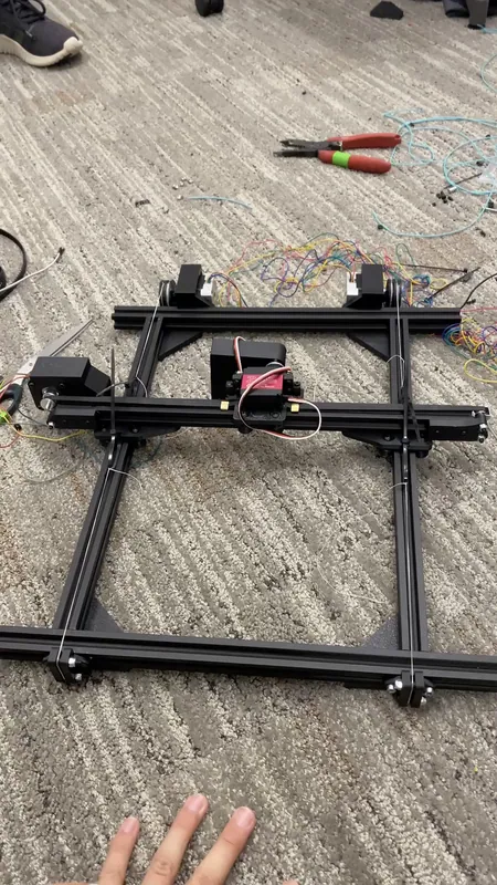 The assembled gantry from above: two Y motors at the far end, the beam across the side rails and the red servo on its carriage. The floss runs along both side rails