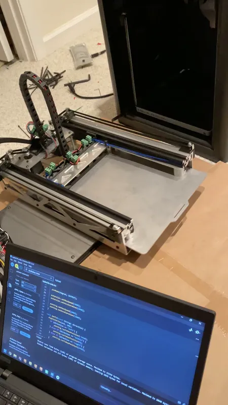 A custom plate held by the magnets after coming out of the printer, the firmware open on the laptop (August 2024)