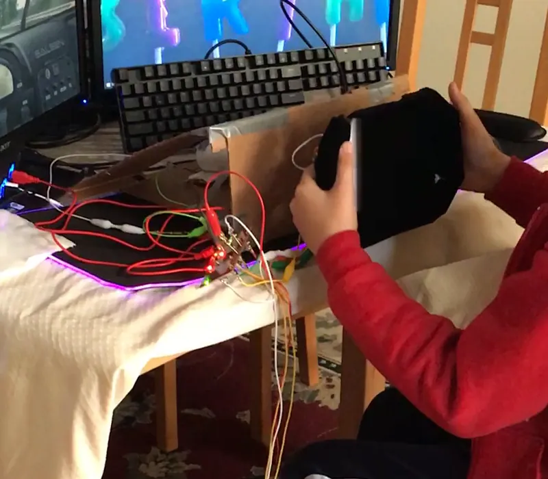 The second version: a duct-taped cardboard wheel on a cardboard stand, with alligator clips running to the board on the desk