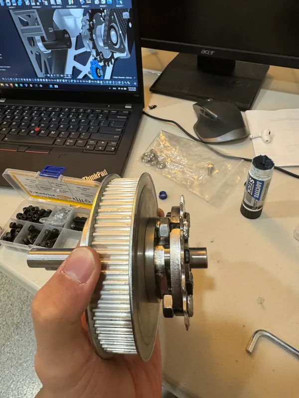 Axle 2: the 72T pulley, keyed hub, adapter plate and sprocket on one shaft, with the CAD behind