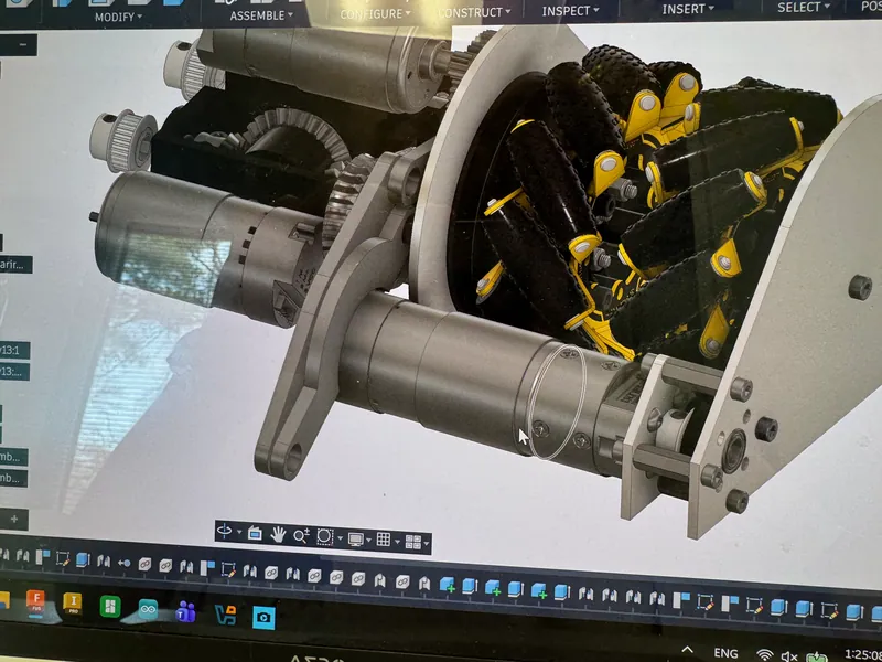 March 14, 2026: a drive pod in the CAD with its mecanum wheels and motors, and the PTO gearing beside it