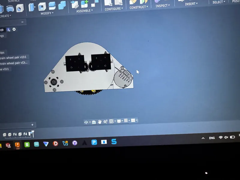 From the side: two black gearbox housings geared together above the pod plate
