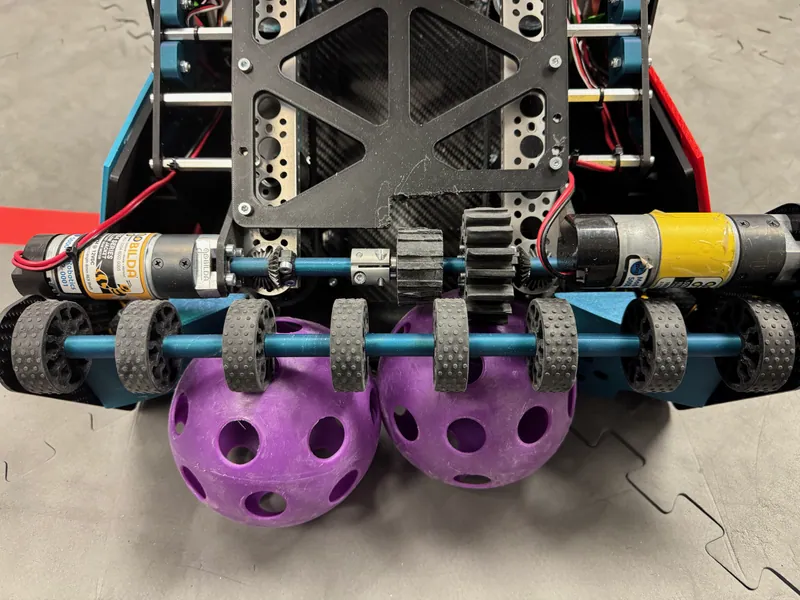 The intake: eight compliant wheels on one shaft across the front, with two balls against it