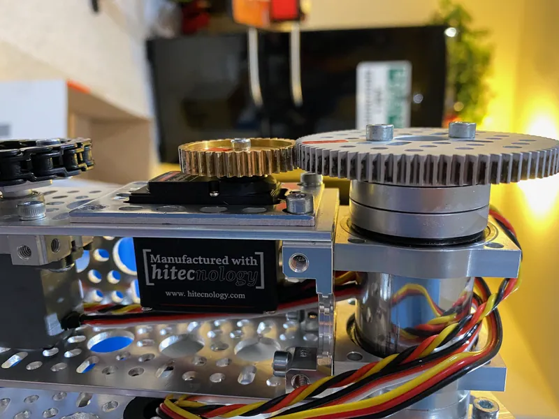 February 8: under a plate, a servo's brass gear meshes with a large gear on a round bearing housing
