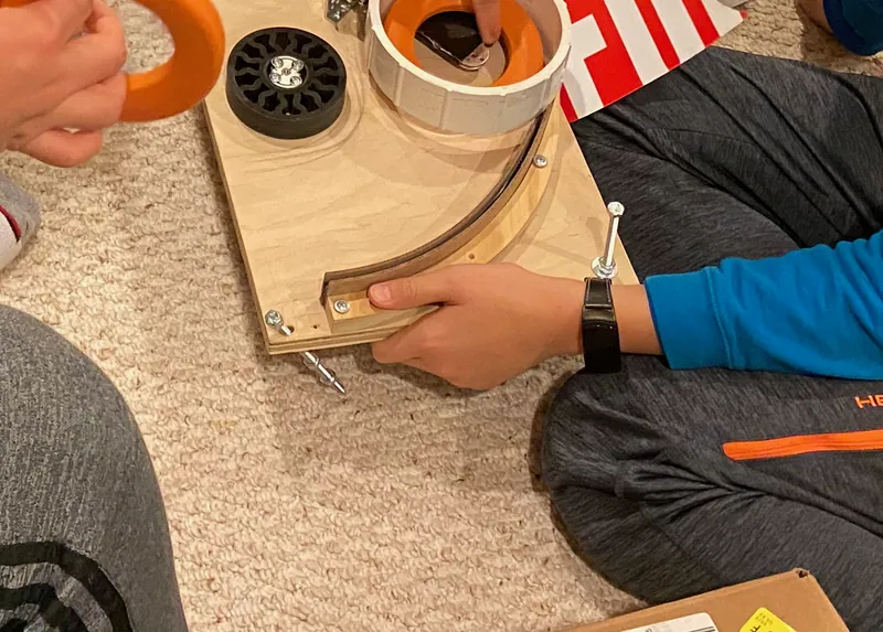 Day 18: the shooter plate on the carpet: the wheel, the white cup with a ring in it, and the curved rail