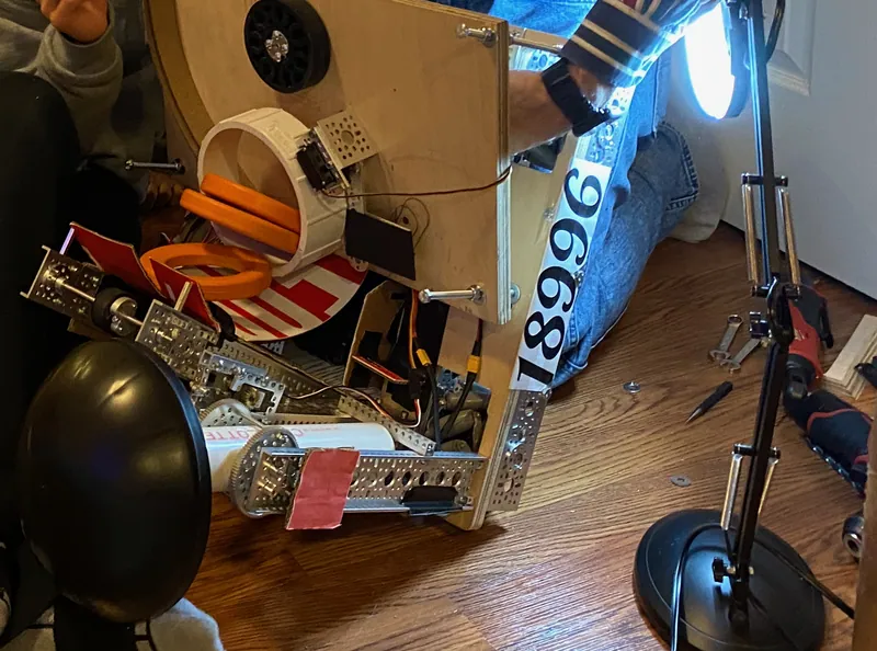 The robot tipped up for work, shooter plate toward the camera: wheel at the top, rings in the cup, the servo beside it