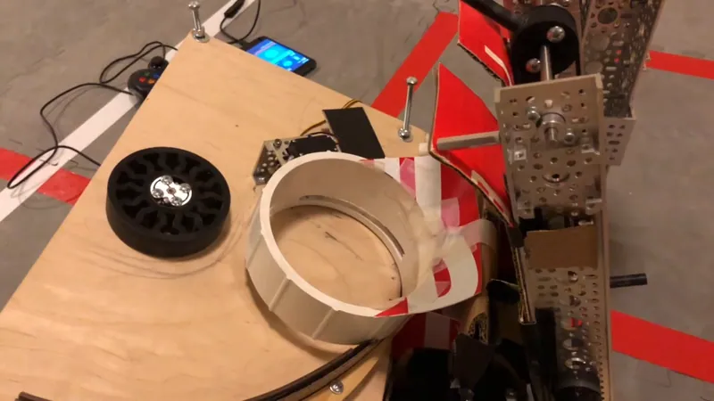 The shooter plate from above: the black wheel, the white cup with three rings in it, the servo on its bracket, and the curved rail along the edge