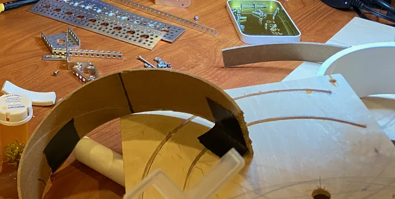 Day 10: arcs cut from a cardboard concrete-form tube, next to plywood with curved slots