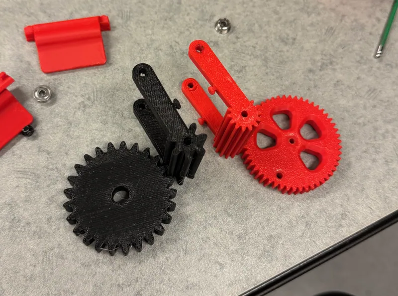 Version 1 (red, module 1) next to version 2 (black, module 2), each gear with an arm and its pinion, Aug 1